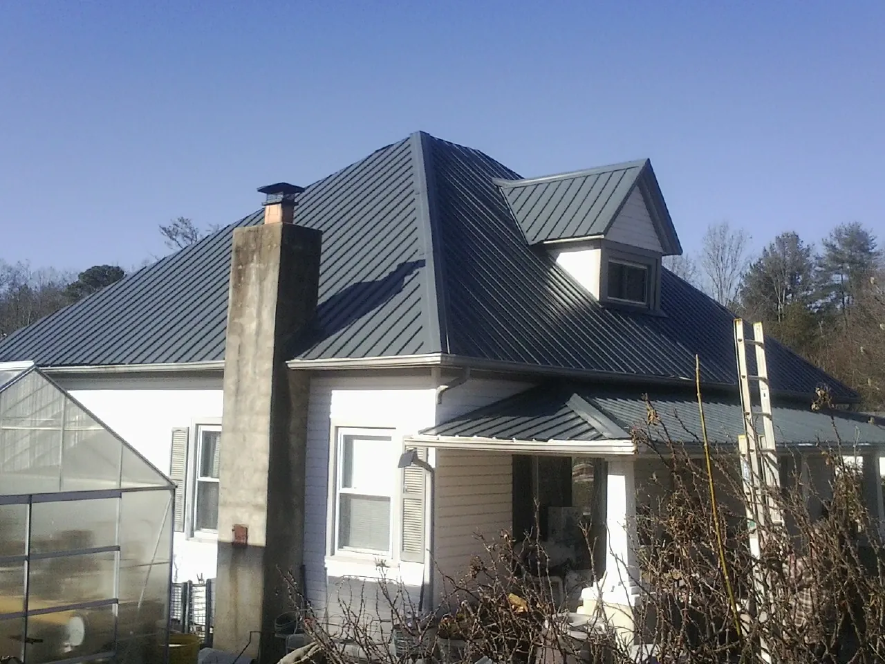Dark blue standing seam metal roof on a white farmhouse with dormer — Slate & Tile Roof Repair by Roofing Brothers in Kingsport