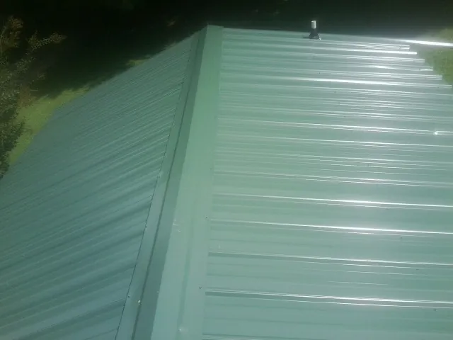 New green metal panels meeting at the ridge of a roof — Flat Roof Repair work by our crew in Kingsport