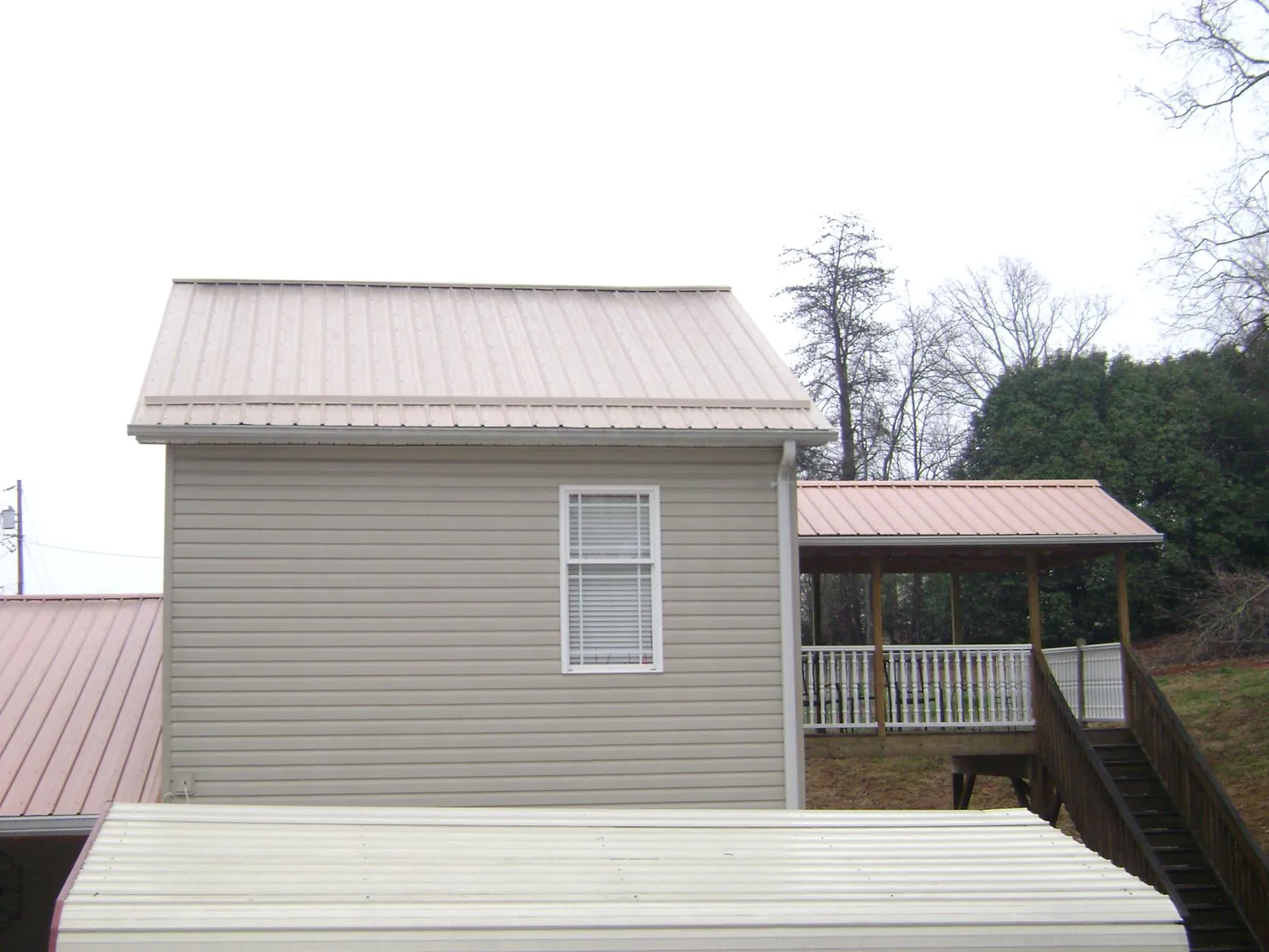 Tan metal roofs on a two story addition and attached porch, from a Roof Replacement job in Kingsport